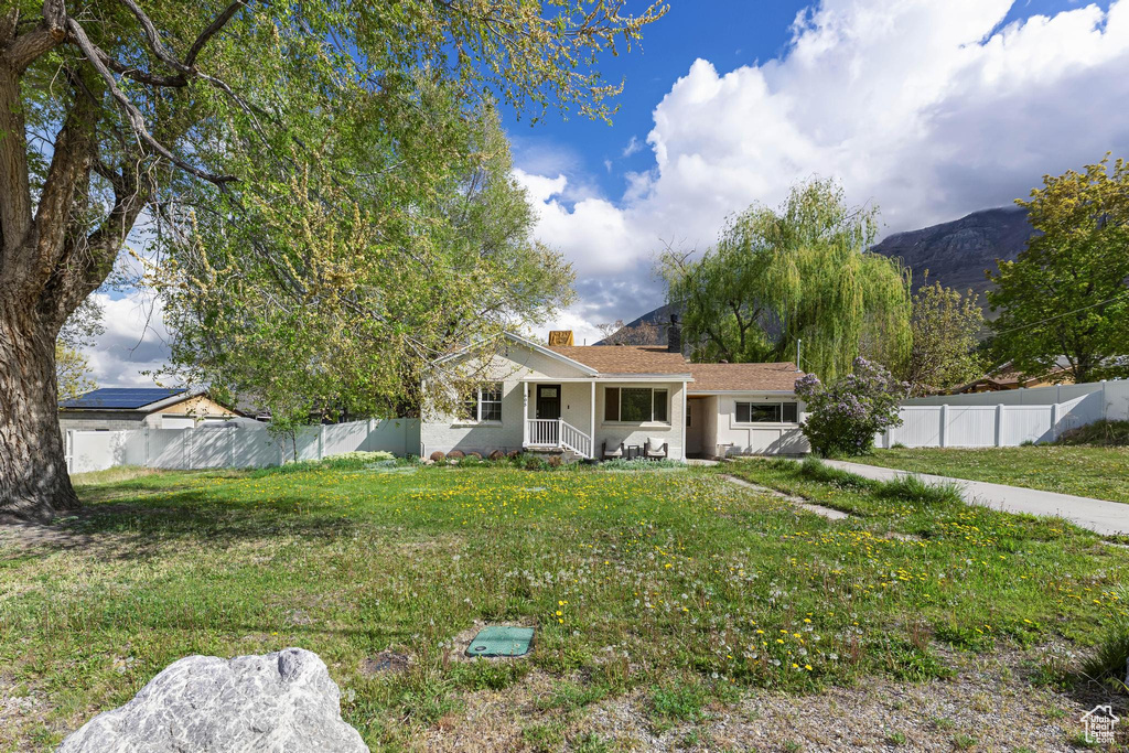 View of front of house featuring a porch, a chimney, fence private yard, and a front yard