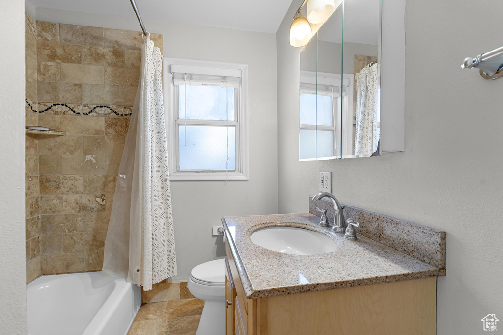 Bathroom with toilet, shower / bathtub combination with curtain, and vanity