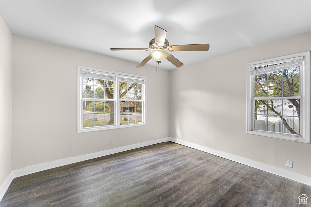 Empty room featuring baseboards, a ceiling fan, and dark wood-style flooring