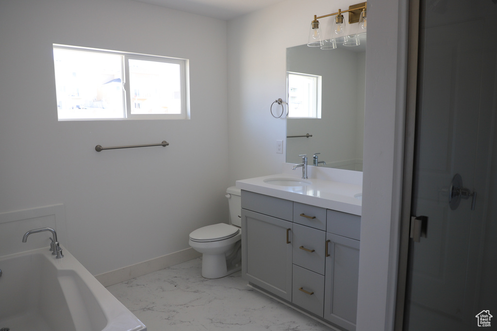 Bathroom featuring vanity, toilet, marble finish floor, a tub, and baseboards