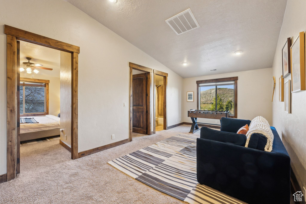 Living room with visible vents, lofted ceiling, light carpet, a textured ceiling, and a ceiling fan
