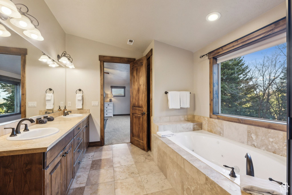 Bathroom with a whirlpool tub, a sink, vaulted ceiling, and double vanity