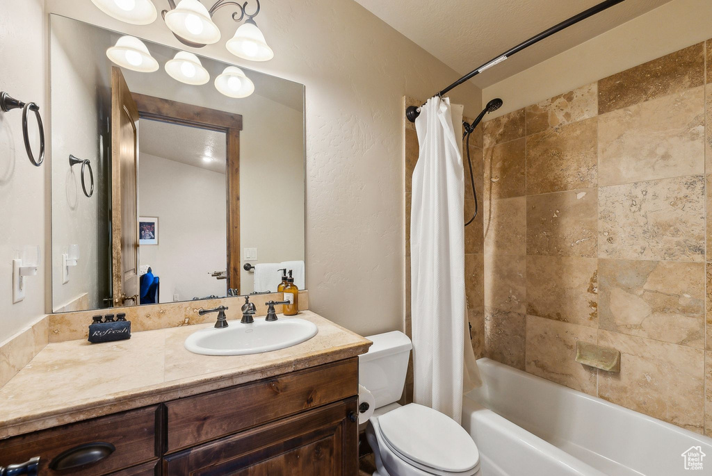 Bathroom featuring vanity, shower / tub combo with curtain, and toilet