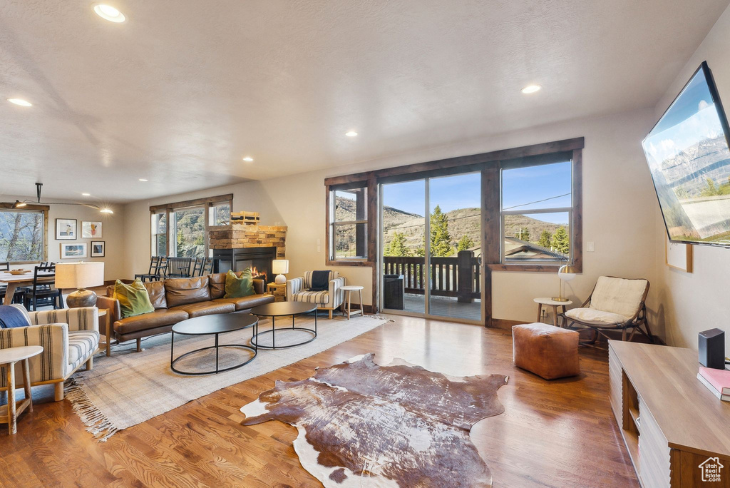 Living room with recessed lighting, a glass covered fireplace, and wood finished floors