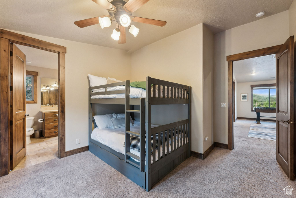 Carpeted bedroom with baseboards, a ceiling fan, and connected bathroom
