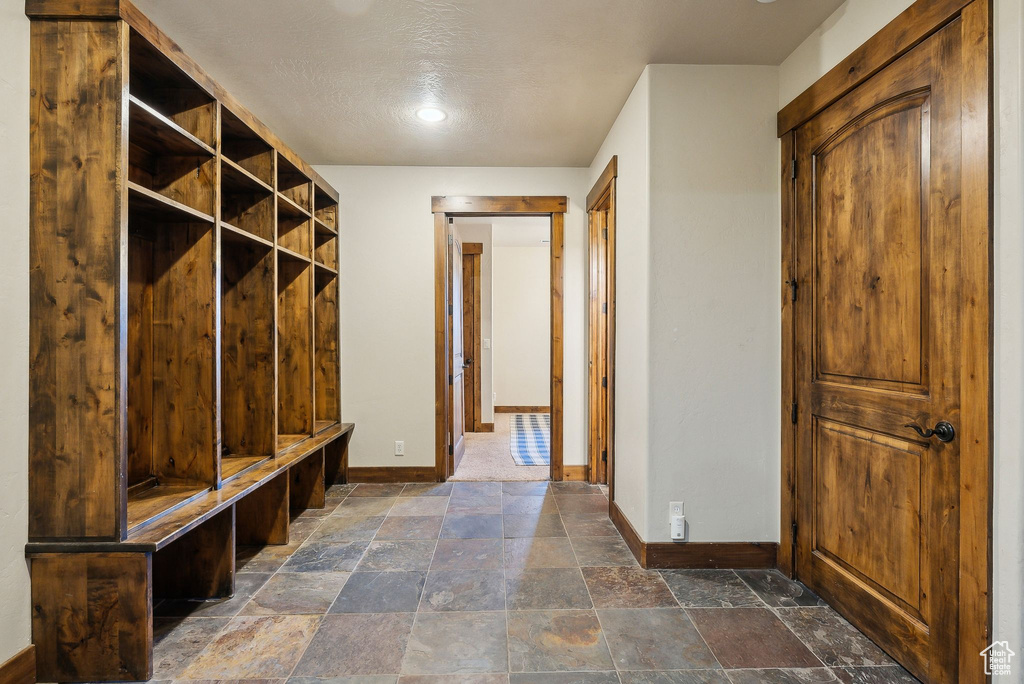 Mudroom featuring baseboards and stone tile flooring
