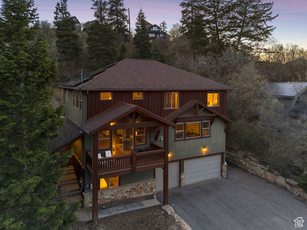 View of front of property featuring aphalt driveway, a shingled roof, solar panels, and a garage