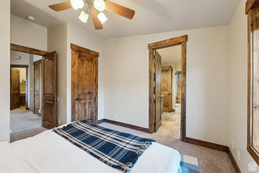 Bedroom with a ceiling fan, baseboards, light colored carpet, and ensuite bathroom