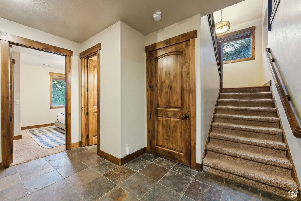 Stairs featuring baseboards, a healthy amount of sunlight, and stone tile flooring