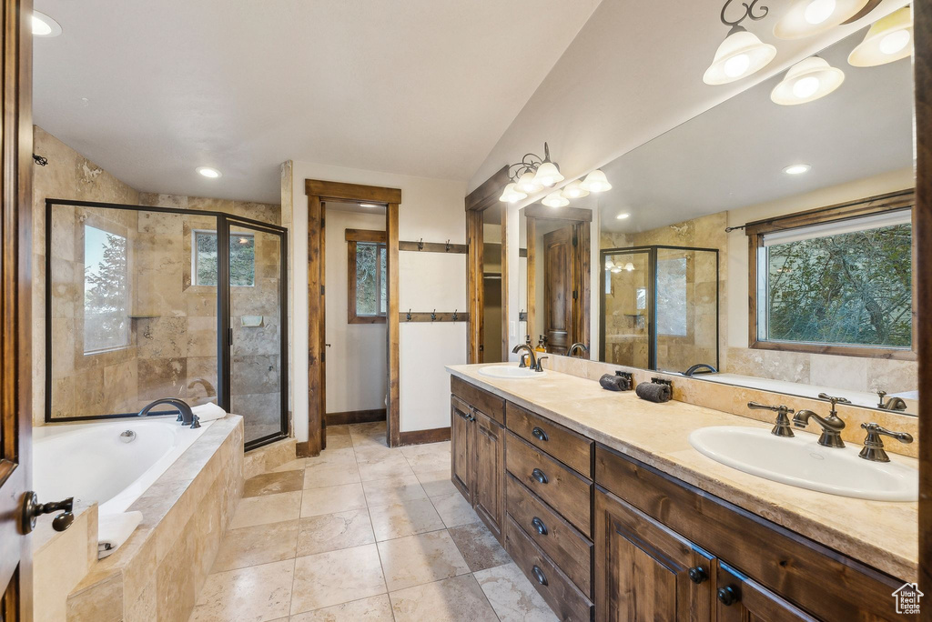 Full bath with double vanity, a bath, a shower stall, a sink, and baseboards