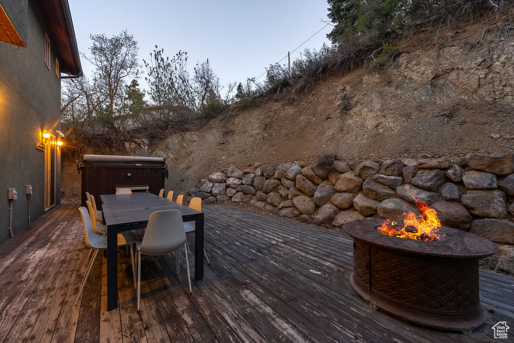 Wooden terrace with outdoor dining space, a hot tub, and an outdoor fire pit
