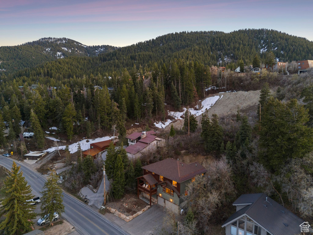 Aerial view at dusk featuring a mountain view and a wooded view