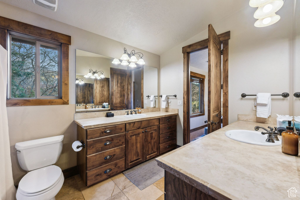 Bathroom featuring visible vents, vanity, toilet, tile patterned floors, and vaulted ceiling