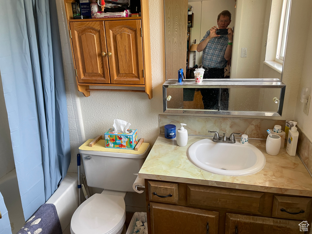 Bathroom featuring toilet, shower / bath combination with curtain, and vanity