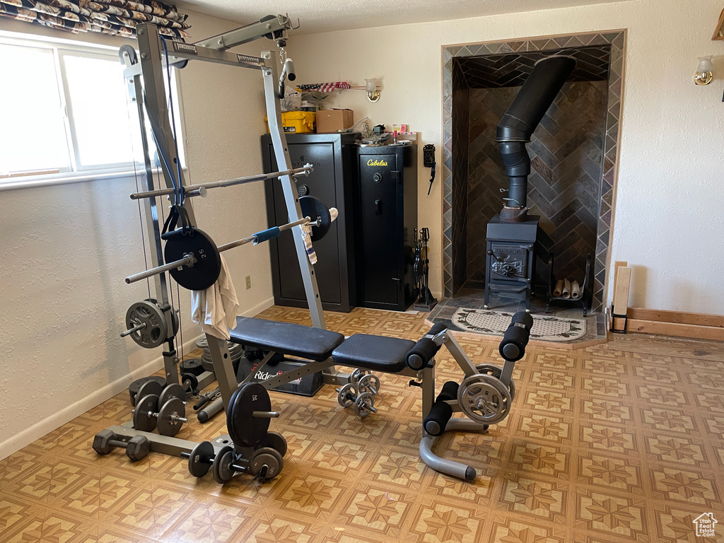 Exercise area with baseboards, a wood stove, and tile patterned floors
