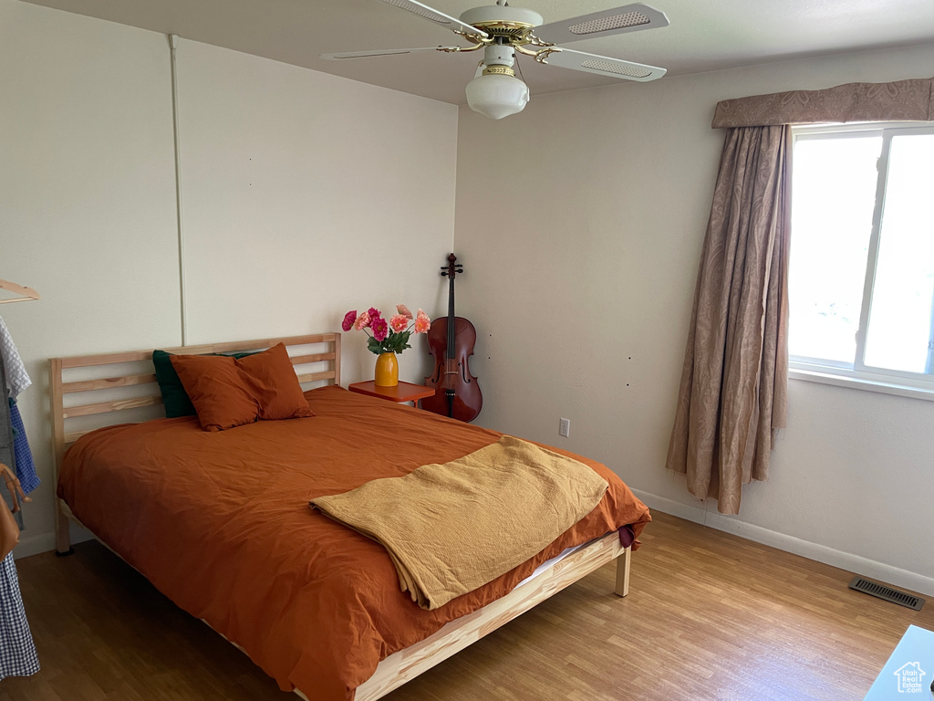 Bedroom featuring baseboards, ceiling fan, wood finished floors, and visible vents