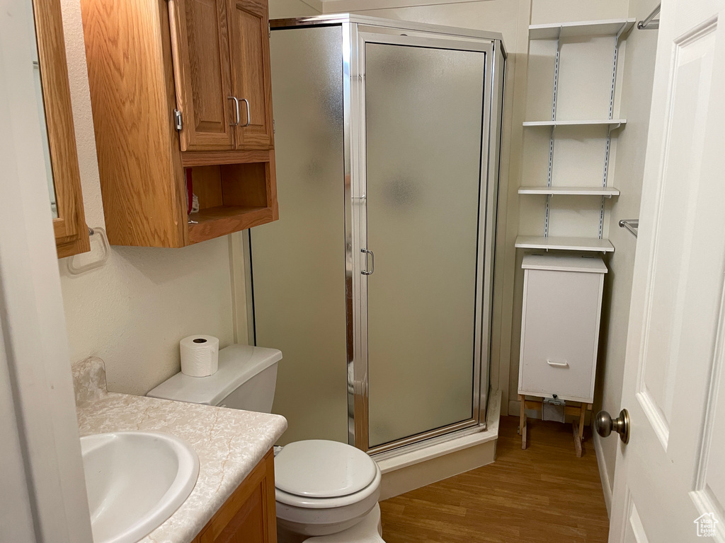Full bath with vanity, a stall shower, toilet, and wood finished floors