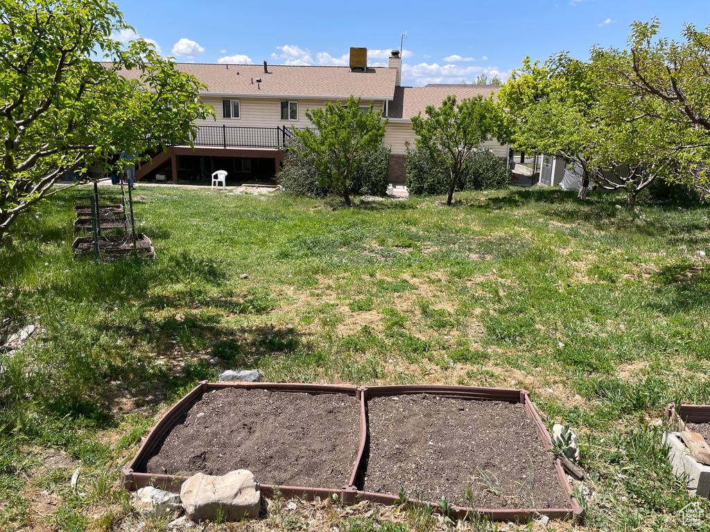 View of yard featuring a wooden deck, stairs, and a garden