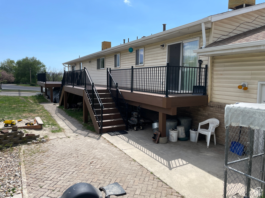 Back of house with stairway, a deck, a chimney, and a patio