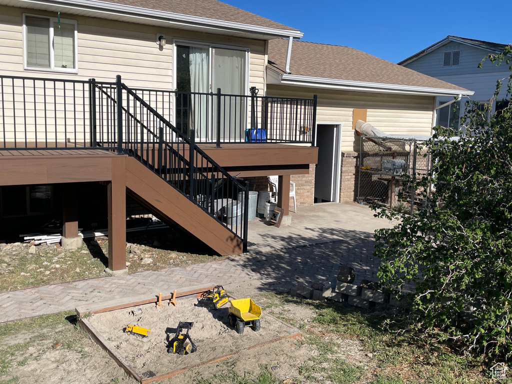 Back of property with a deck, stairs, and roof with shingles