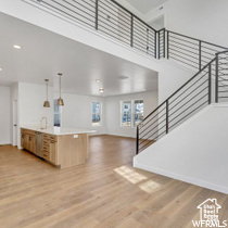 Kitchen with baseboards, open floor plan, light wood finished floors, and a towering ceiling