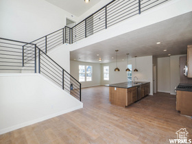 Kitchen with a towering ceiling, dark countertops, brown cabinets, wood finished floors, and open floor plan