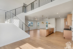 Kitchen featuring a high ceiling, a wealth of natural light, light wood-style floors, and light brown cabinets