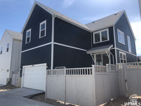 View of front of property featuring an attached garage, fence, and driveway