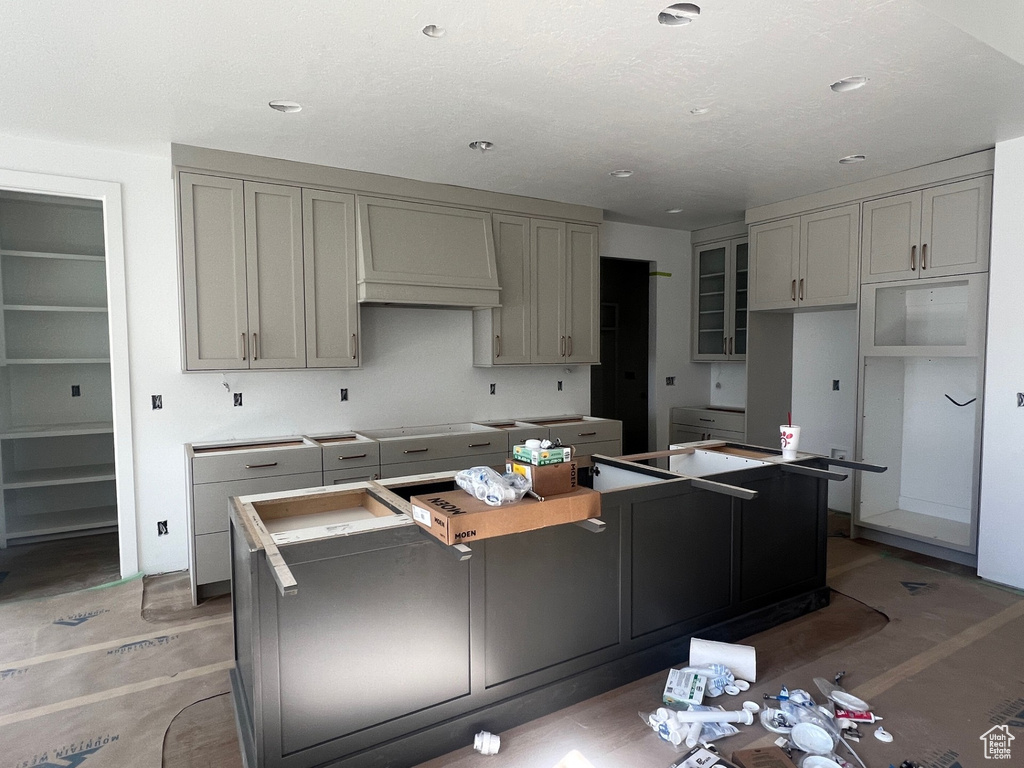 Kitchen featuring a kitchen island, gray cabinets, custom exhaust hood, light wood finished floors, and recessed lighting