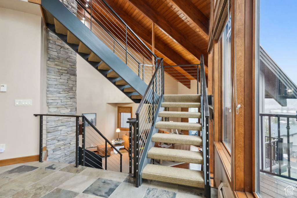 Stairs with beamed ceiling, baseboards, and wooden ceiling