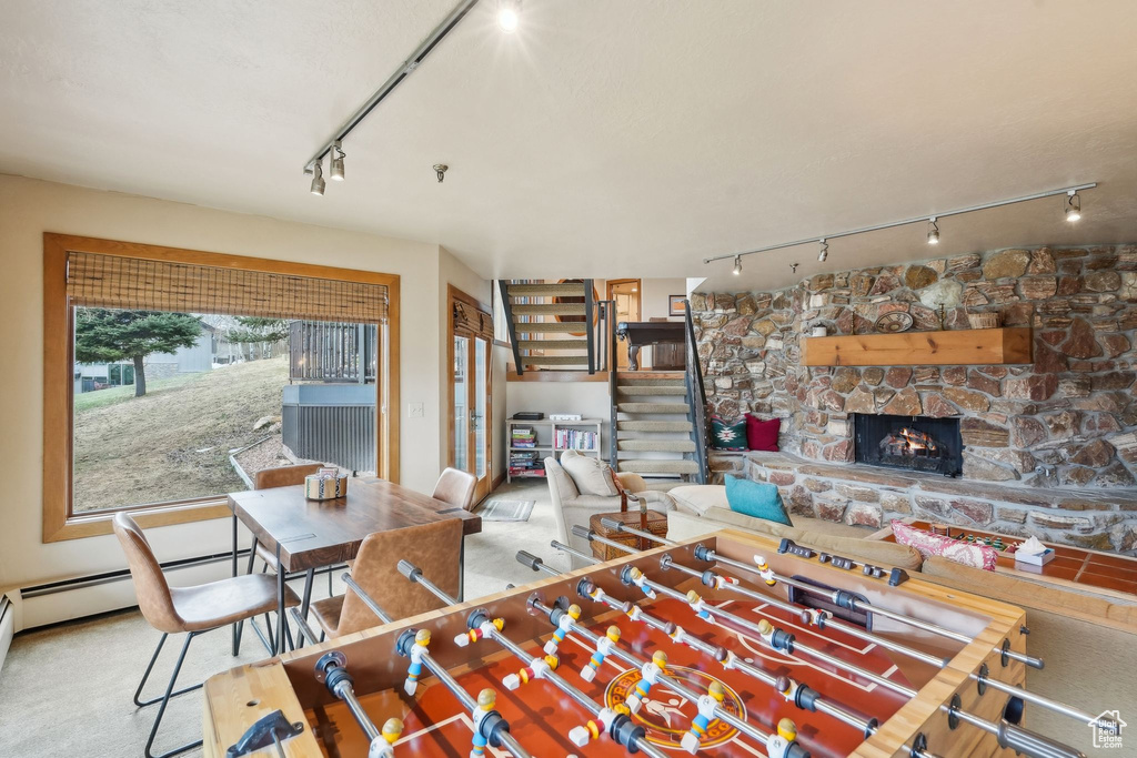 Playroom with carpet flooring, a stone fireplace, and track lighting