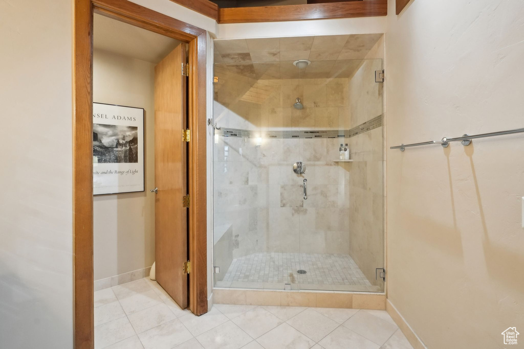 Bathroom featuring a shower stall, tile patterned floors, and baseboards