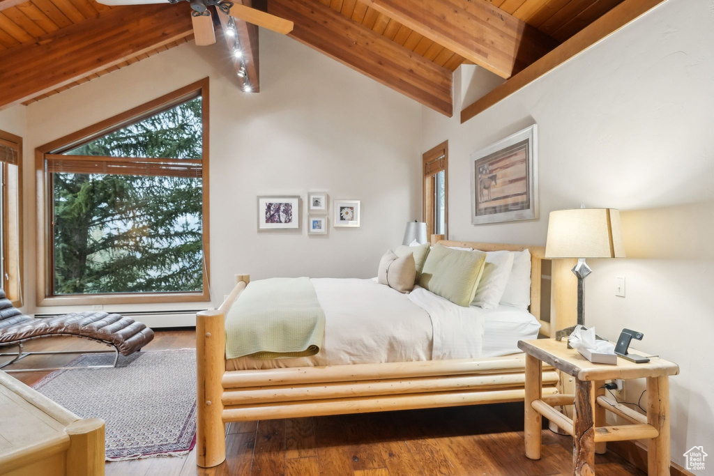 Bedroom with baseboard heating, wood ceiling, wood finished floors, and vaulted ceiling with beams