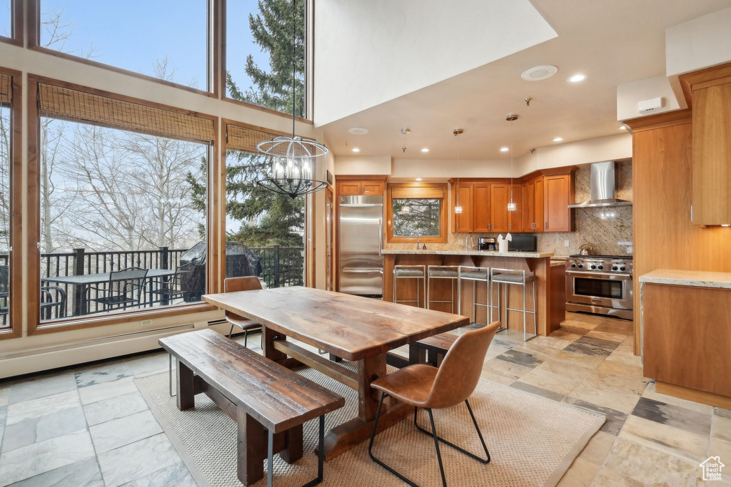 Dining area featuring a high ceiling, recessed lighting, an inviting chandelier, and stone finish flooring