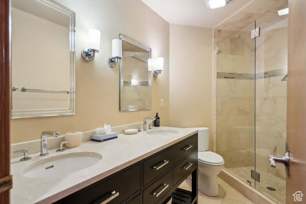 Full bathroom featuring a sink, toilet, double vanity, and a stall shower