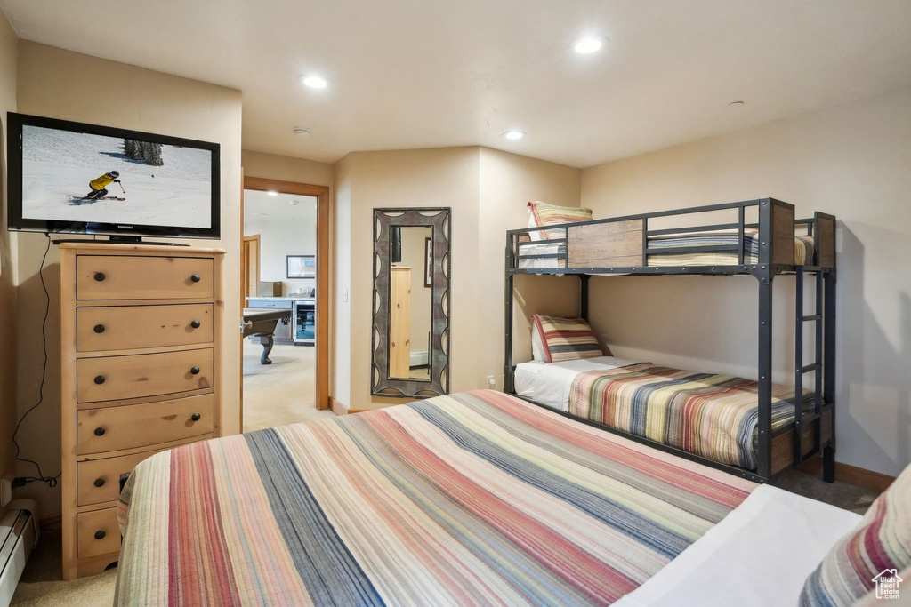 Bedroom with light colored carpet, recessed lighting, beverage cooler, a baseboard radiator, and baseboards