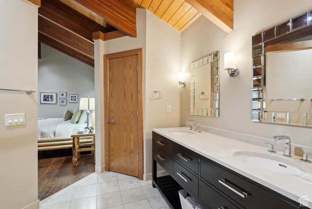 Ensuite bathroom featuring a sink, double vanity, tile patterned flooring, and wood ceiling