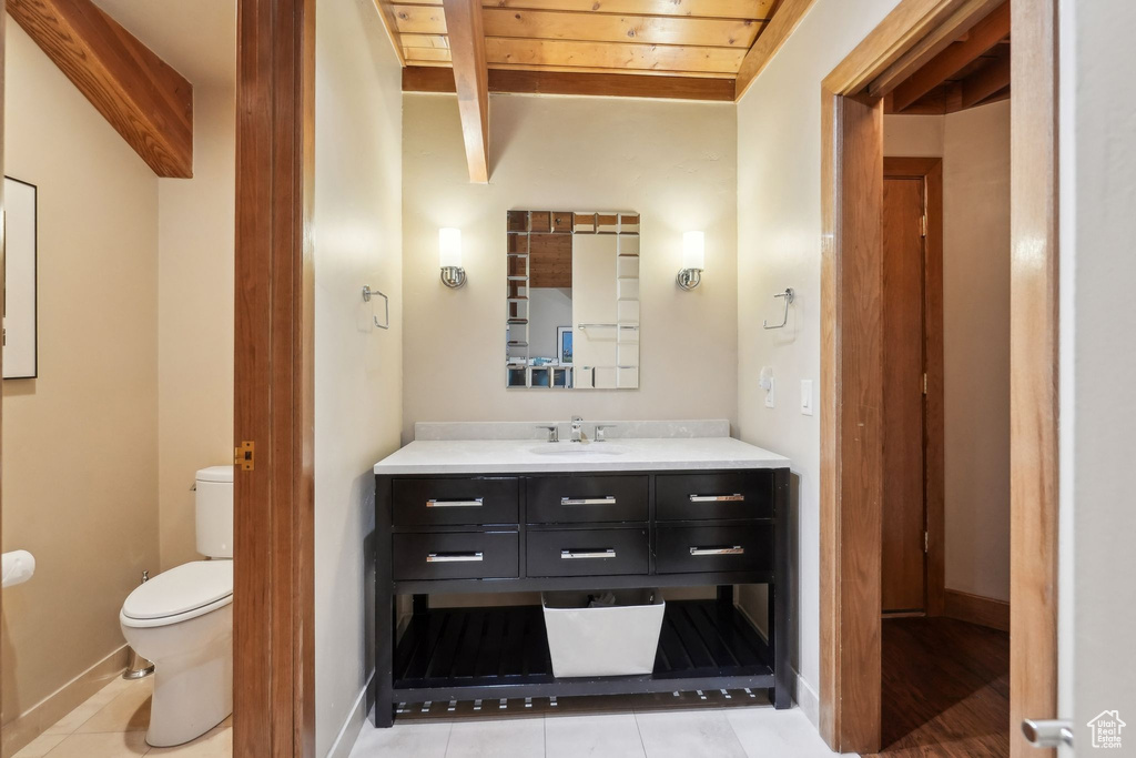 Bathroom featuring toilet, vanity, baseboards, and beam ceiling