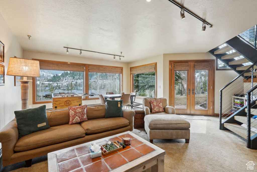 Carpeted living area with stairway, french doors, and a textured ceiling