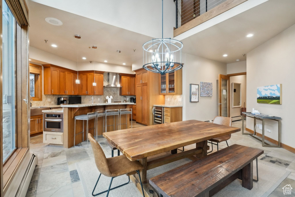 Dining space with baseboard heating, an inviting chandelier, beverage cooler, and recessed lighting