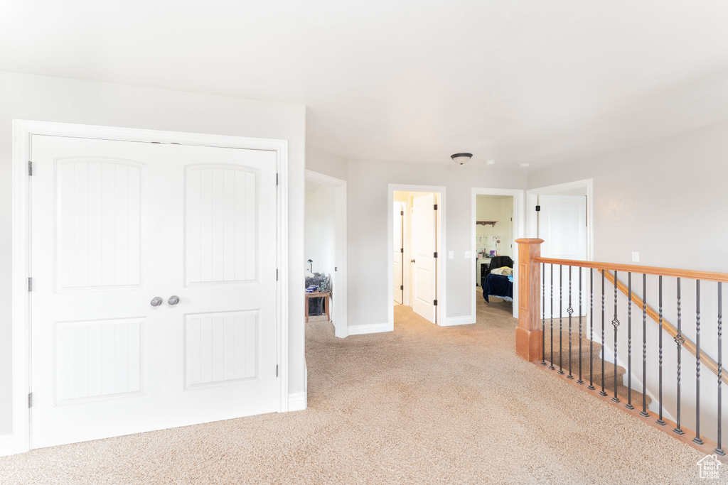 Hall with baseboards, an upstairs landing, and light colored carpet