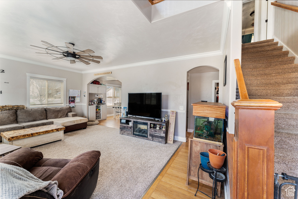 Living room with arched walkways, ornamental molding, a ceiling fan, and wood finished floors