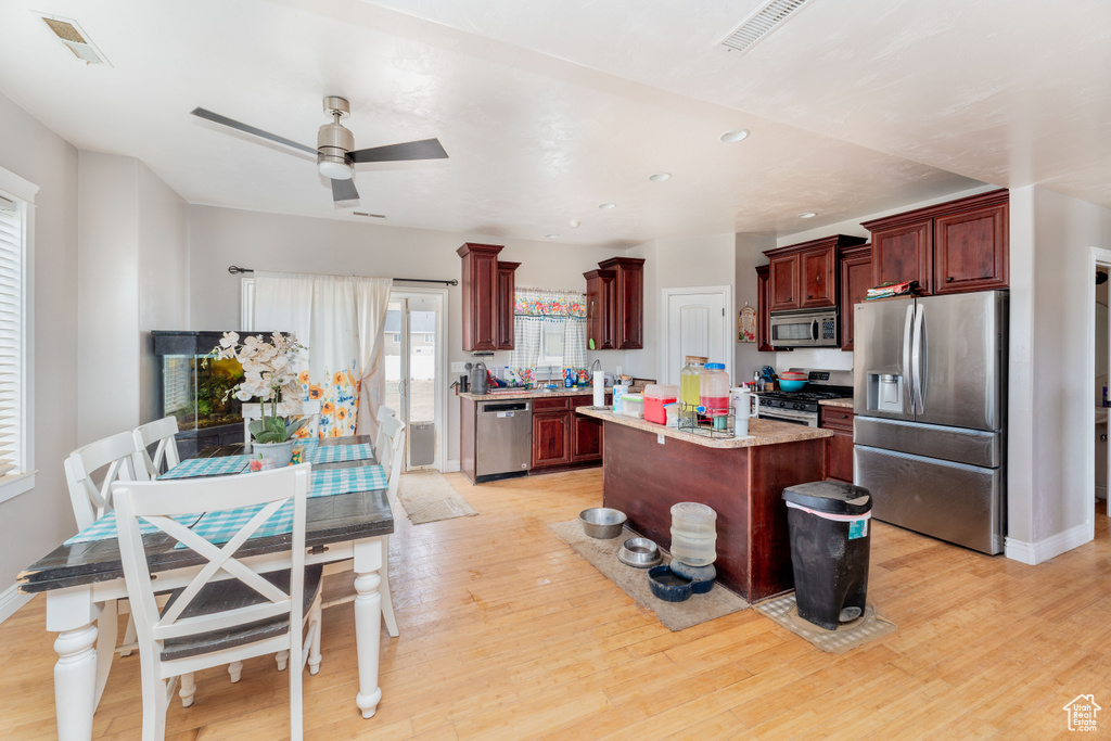 Kitchen with visible vents, appliances with stainless steel finishes, light wood finished floors, and reddish brown cabinets