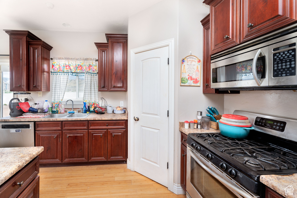 Kitchen featuring light wood-style floors, a sink, dark brown cabinets, and stainless steel appliances
