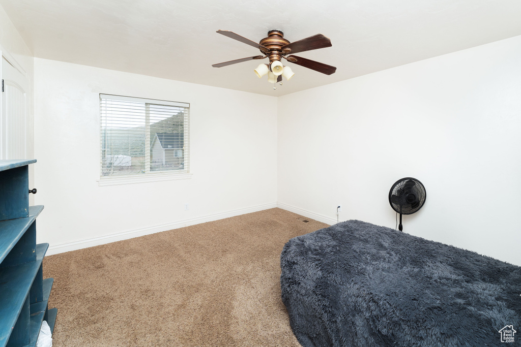 Carpeted bedroom with baseboards and a ceiling fan