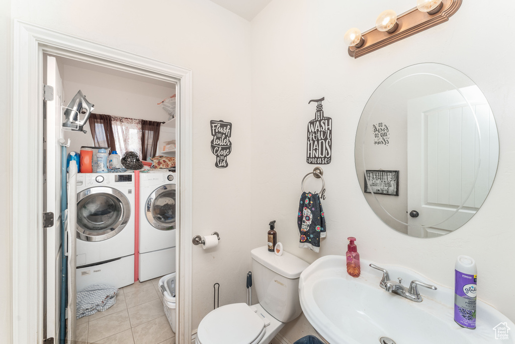 Bathroom with tile patterned flooring, a sink, washer and dryer, and toilet