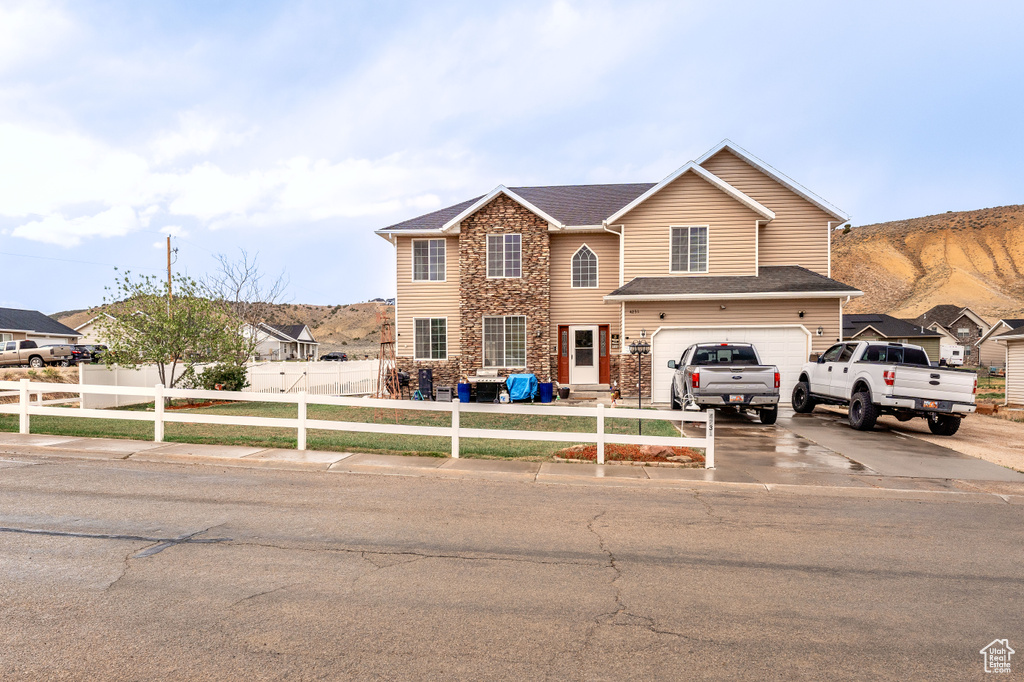 Traditional home with driveway, fence private yard, a garage, a mountain view, and stone siding