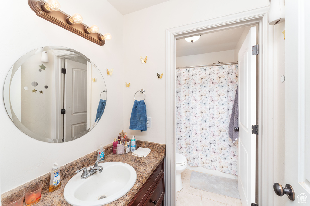 Bathroom featuring vanity, tile patterned floors, toilet, and a shower with shower curtain