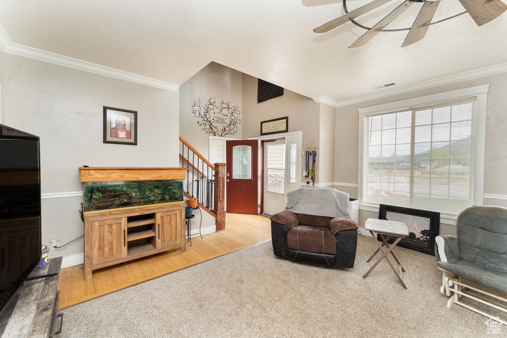 Living area featuring crown molding, ceiling fan, wood finished floors, and stairway