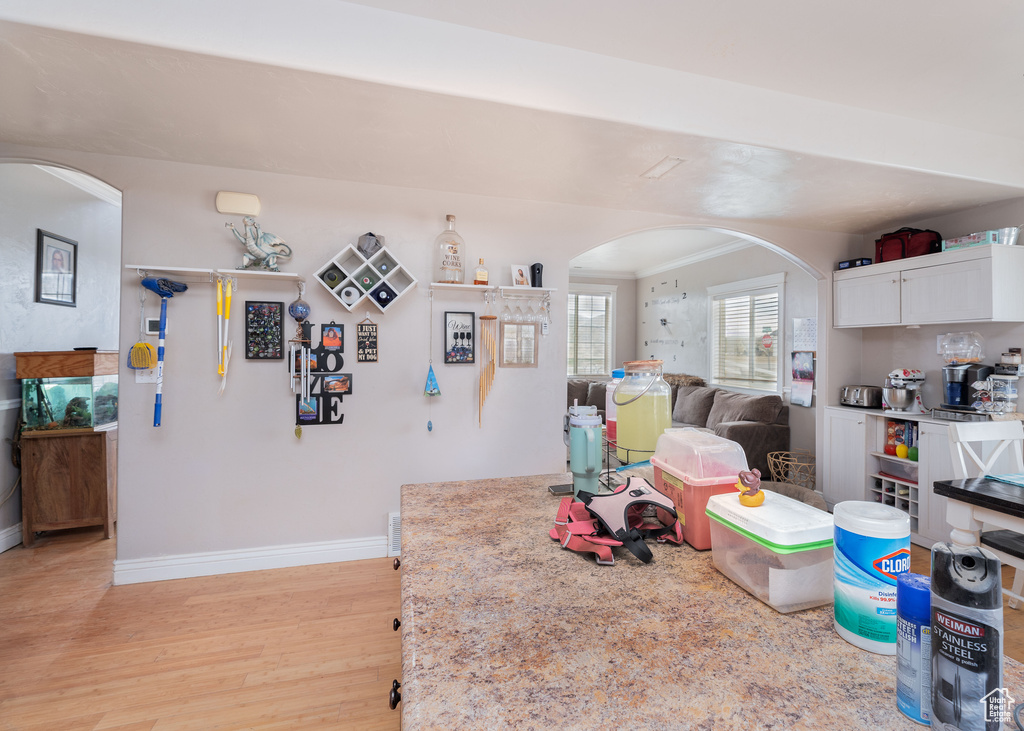 Playroom with arched walkways, baseboards, and light wood-style flooring